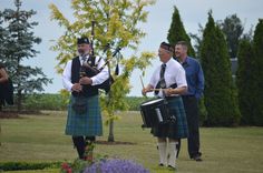 two men in kilts are playing the bagpipes while another man is standing behind them