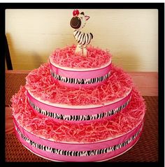 a pink cake with zebras on the top tier and ribbons around the bottom tier