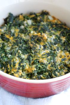 spinach and cheese casserole in a red dish on a white tablecloth