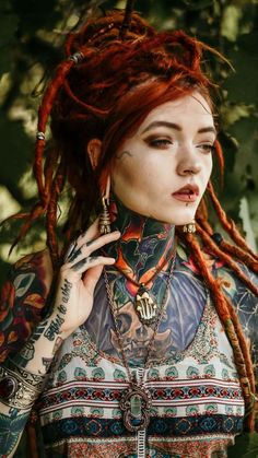 a woman with red dreadlocks and tattoos on her body is posing for the camera