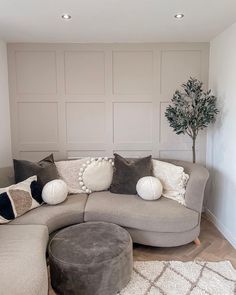 a living room with a large sectional couch and pillows on the floor, next to a potted tree