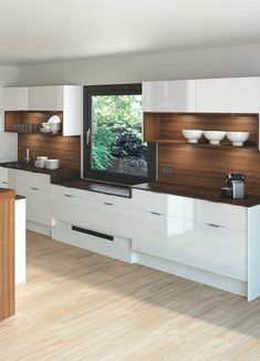 a large kitchen with white cabinets and wood accents on the counter tops, along with a television mounted to the wall