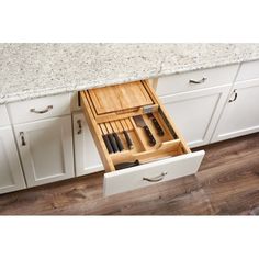 an open drawer in the middle of a kitchen with knives and utensils inside