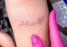 a woman's arm with the word alice tattooed on her left leg and pink gloves