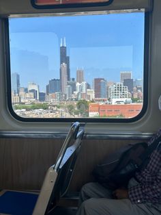 a man sitting on a train looking out the window with a city skyline in the background