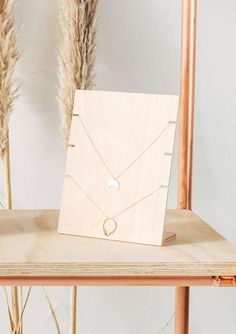 a wooden box with a necklace on it sitting on a table next to dried grass