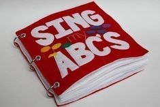 a red and white book with the words sing my abc's on it sitting on a table