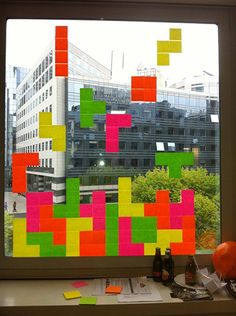 a window that has been decorated with colorful sticky notes in front of a cityscape