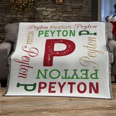 a white blanket with red and green letters on it sitting in front of a couch