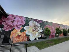 a large mural on the side of a building with pink and yellow flowers painted on it