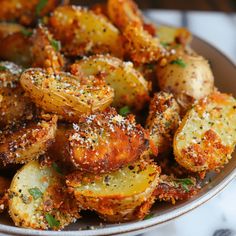 a bowl filled with fried potatoes covered in seasoning and sprinkled with parmesan