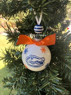 a christmas ornament hanging from a tree with an orange bow on it's head