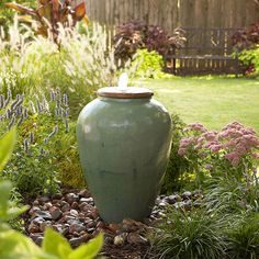 a large green vase sitting in the middle of a garden