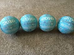 three blue balls with names on them sitting on the floor