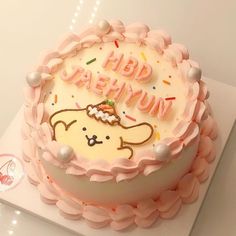 a white cake with pink icing and decorations on it's top that says happy birthday