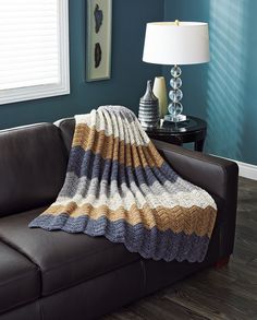 a couch with a blanket on top of it in a living room next to a lamp