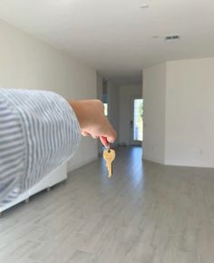 a person is holding a house key in the middle of an empty room with hardwood floors