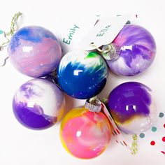 five colorful ornaments on a white surface with confetti sprinkles