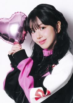 a woman holding a heart shaped balloon in her right hand and posing for the camera