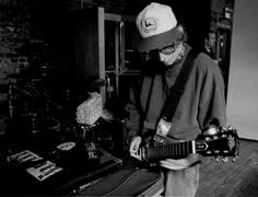 a man in a hat and glasses playing an electric guitar