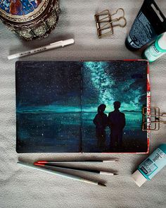 an open notebook with two people looking at the stars in the night sky on it