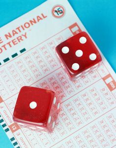 two red dices sitting on top of a paper with the national lottery written in it