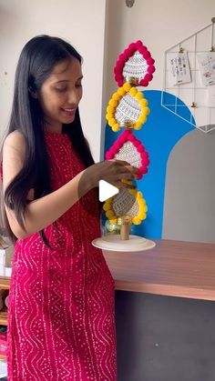 a woman standing in front of a table holding a vase