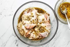 two bowls filled with food sitting on top of a white marble counter next to a silver spoon