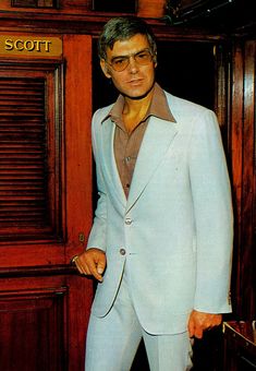 a man in a blue suit standing next to a wooden door