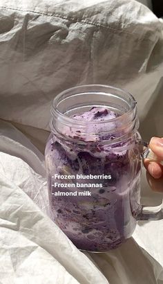 a person is holding a glass jar filled with blueberries and ice cream, while the text reads frozen blueberries frozen bananas almond milk