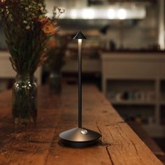 a wooden table topped with a lamp next to a vase filled with flowers