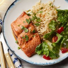 salmon, rice and lettuce on a plate with chopsticks next to it