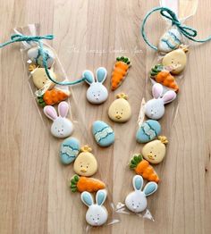 decorated cookies in the shape of bunnies and carrots on a wooden table with blue string