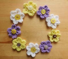 crocheted flowers arranged in the shape of a circle on top of a wooden table