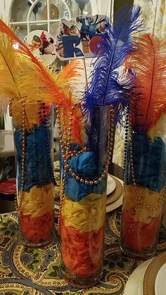 three vases filled with colorful feathers on top of a table