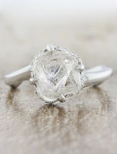 a white diamond ring on top of a wooden table