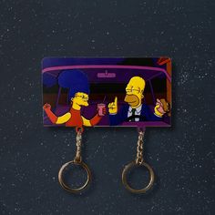 the simpsons car keychain is hanging from two metal hooks on a black surface