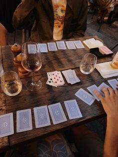 people sitting at a table with cards and wine glasses in front of them on the table