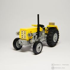 a toy tractor with four wheels on a white surface, in front of a gray background