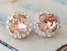 two pairs of pink and white diamond earrings on top of a marble slabd surface