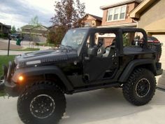 a black jeep parked in front of a house with the door open and lights on