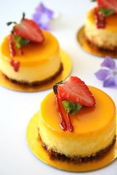 small cheesecakes with strawberries on top and flowers in the backgroun