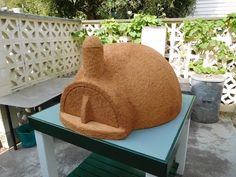 a large rock sitting on top of a green table next to a white picket fence