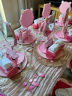 a table set up with pink and white plates, napkins, and other items