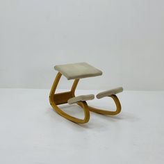 a white chair sitting on top of a white floor next to a wooden foot stool