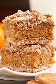 three pieces of cake sitting on top of a white plate next to an orange and cinnamon stick