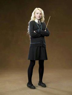 a woman in a black dress is holding a wand and posing for a photo on a brown background