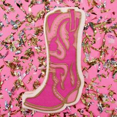 a pink cowboy boot sitting on top of a pile of gold foil confetti