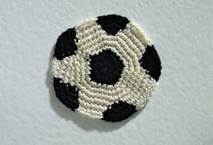 a crocheted black and white soccer ball brooch on a white background,