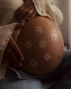 a pregnant woman's belly with daisies painted on it